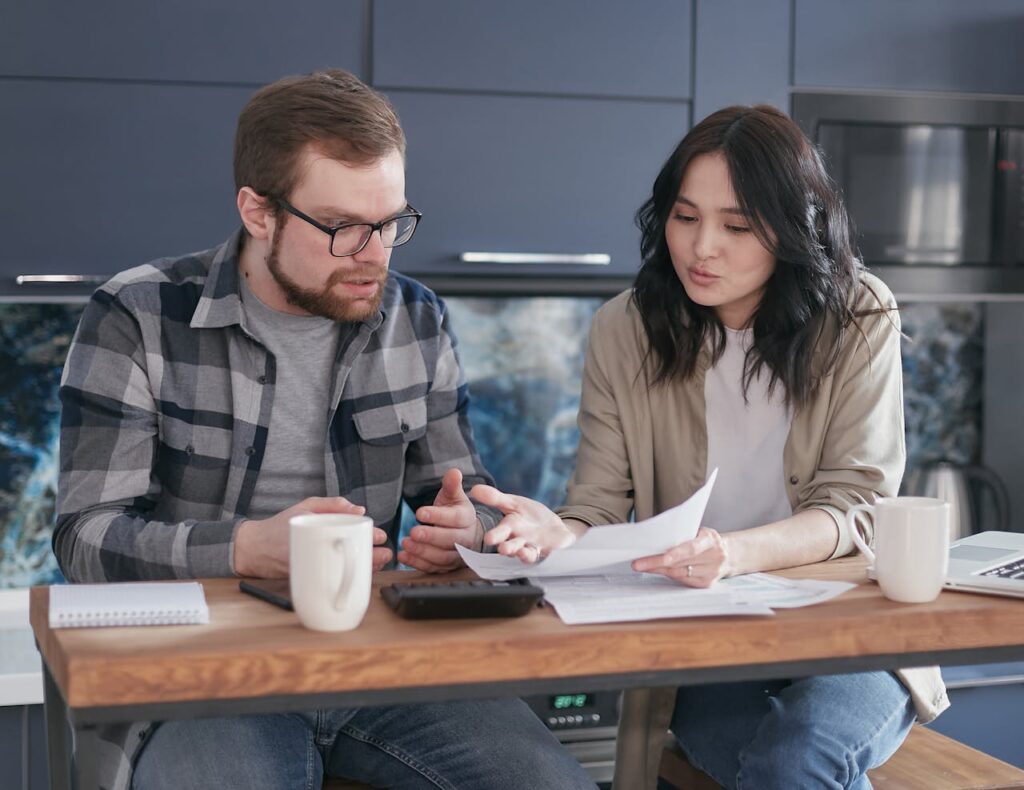 a-couple-sitting-at-a-desk-discussing-about-a-document-6963884 A Couple Sitting at a Desk Discussing About a Document